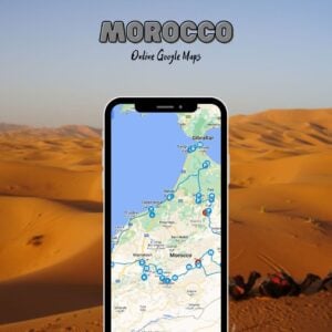 Mobile phone showing our Morocco Google Map with travel pins across the country, placed in front of desert dunes and camels resting in the sand.