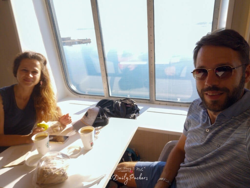Couple enjoying breakfast with Starbucks coffee and snacks by a ferry window with sea views in the background