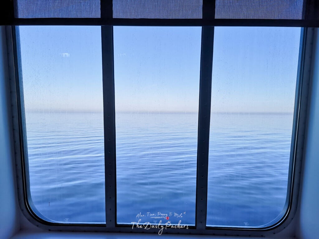 Peaceful sea view through a large ferry window with soft light reflecting off the water