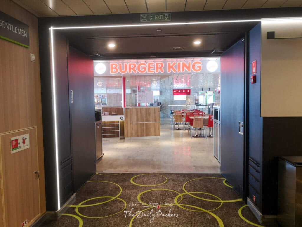 Entrance to a Burger King restaurant inside the ferry, with glowing signage and red seating