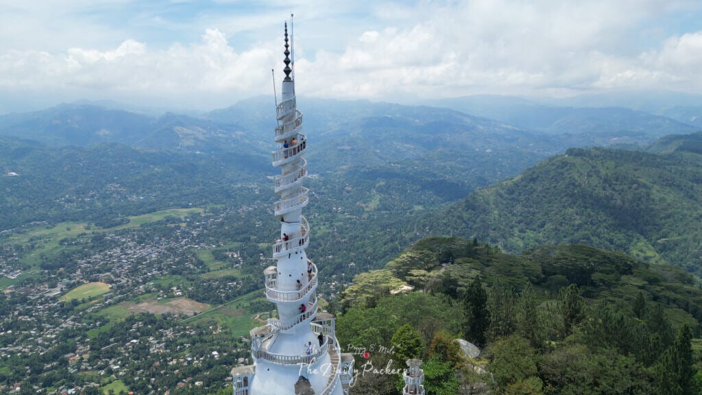 Vue de l'escalier étroit et incurvé et de la balustrade blanche de la tour d'Ambuluwawa, avec des collines verdoyantes en arrière-plan.