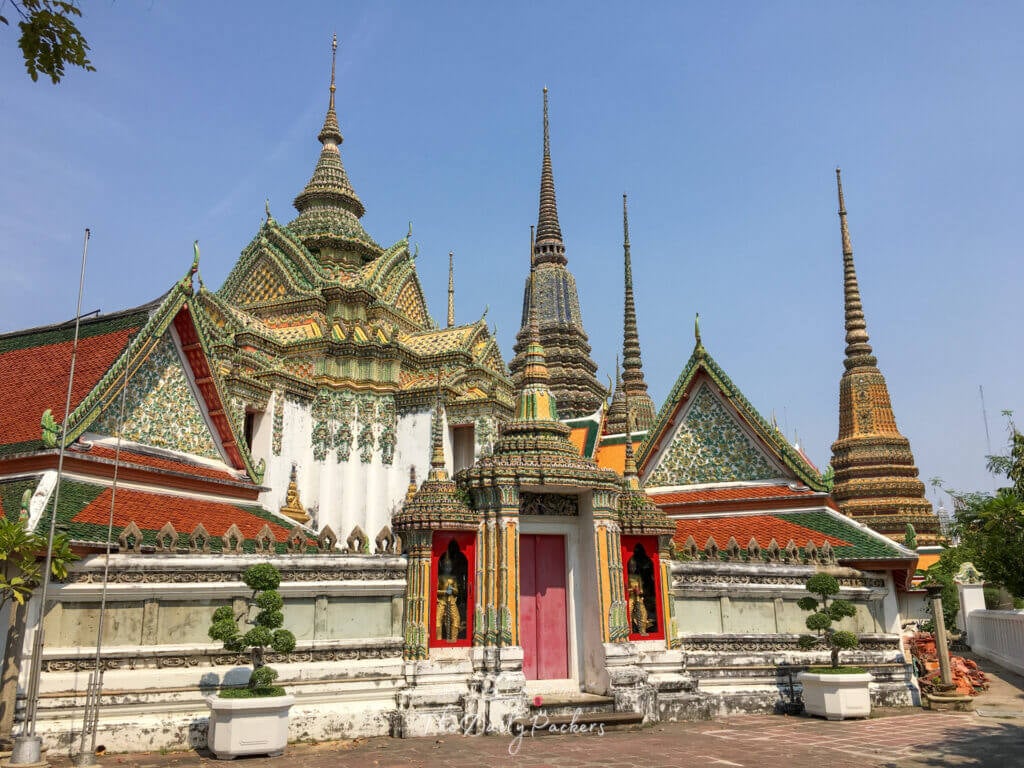 Ornate buildings with colorful tiled roofs and spires in the Grand Palace complex in Bangkok.