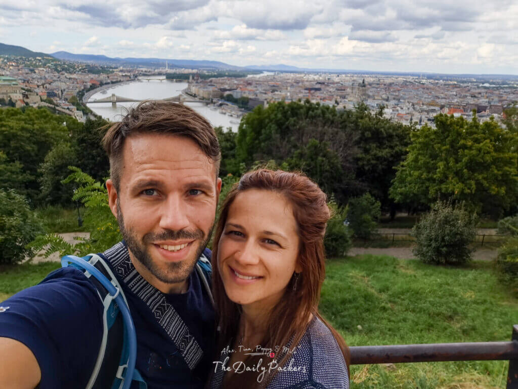 Couple taking a selfie with panoramic view of Budapest and the Danube River from Gellért Hill.
