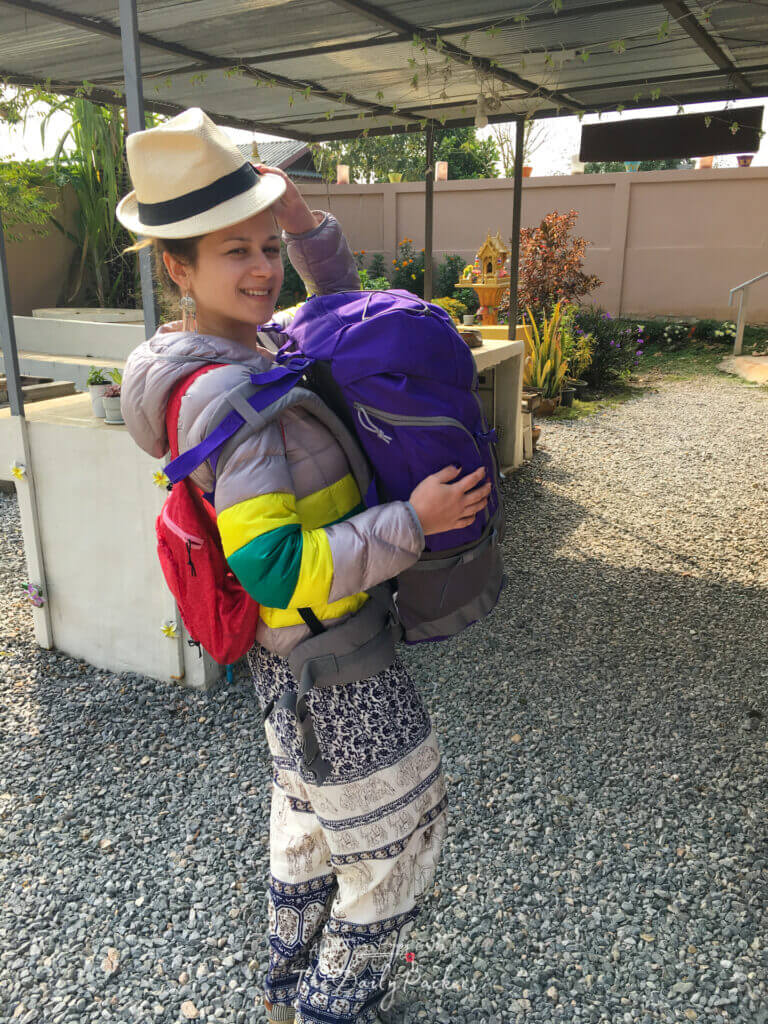 Woman smiling in travel gear and a hat, ready to explore Chiang Mai with her backpack