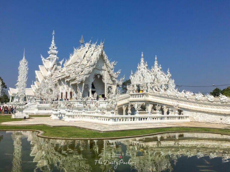 Wide view of Wat Rong Khun, the White Temple in Chiang Rai, reflecting in the surrounding pond.