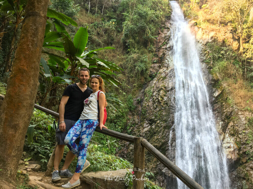 Couple posant sur un sentier de la jungle avec la cascade de Khun Korn derrière eux à Chiang Rai, Thaïlande.