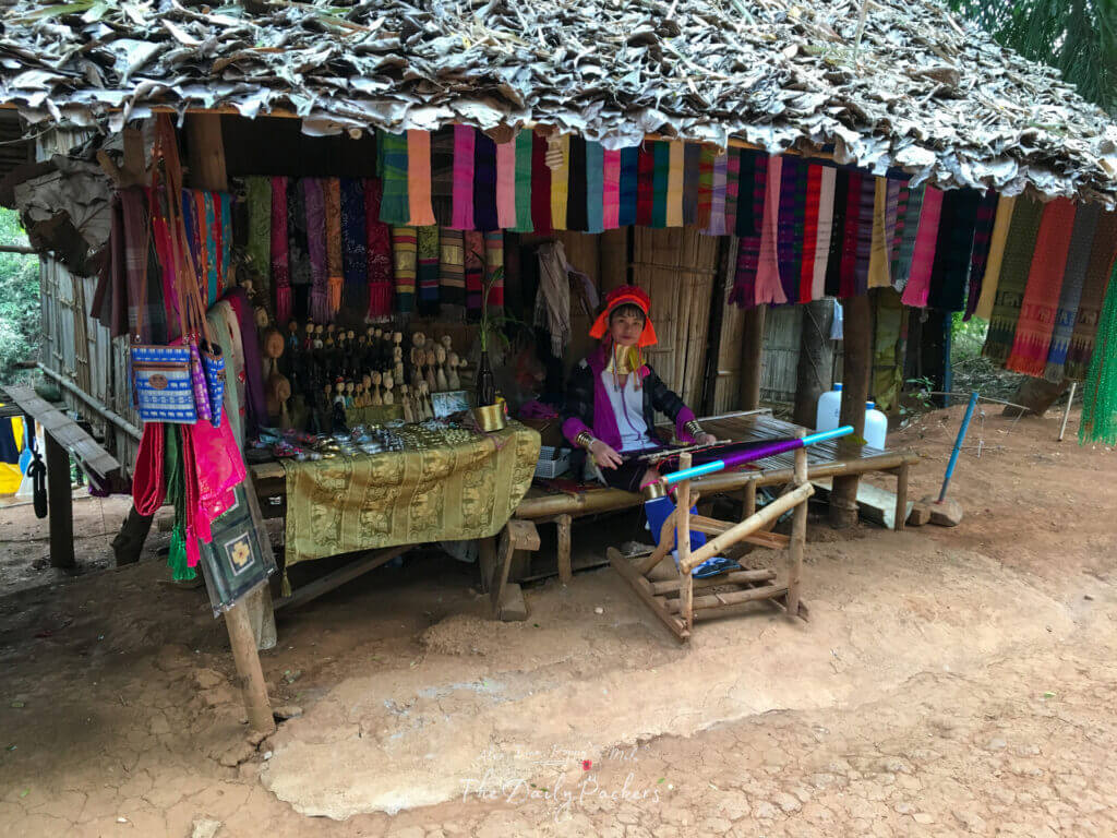Stand traditionnel en bois présentant des écharpes et des objets d'artisanat colorés, tenu par une femme de la tribu Karen Long Neck, dans le nord de la Thaïlande.