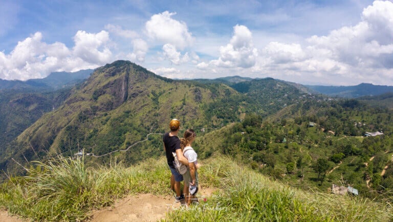 Couple debout au bord du point de vue de Little Adam's Peak, surplombant les montagnes d'Ella