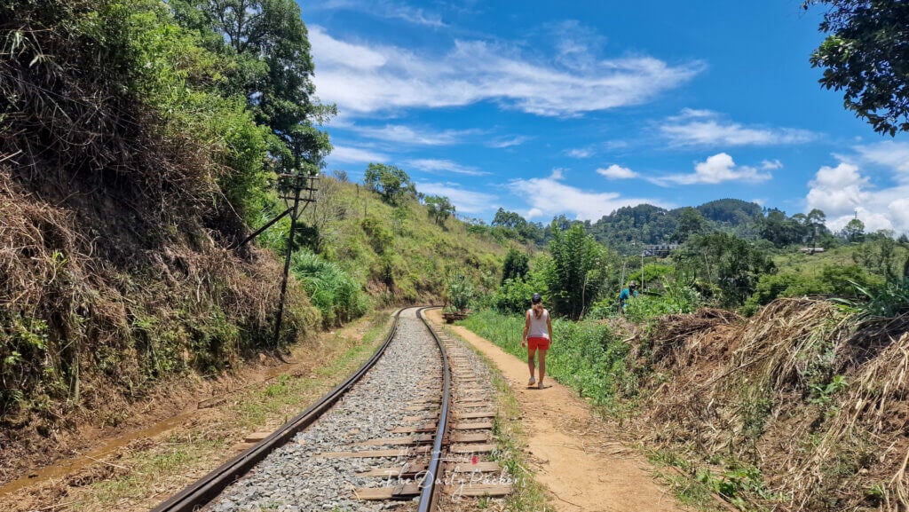 Femme marchant le long de la voie ferrée sous un ciel bleu lumineux près d'Ella, au Sri Lanka.