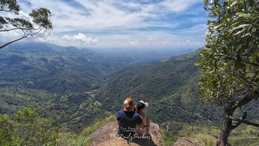 Couple sitting at Ella Rock’s second viewpoint, taking in the sweeping views of the lush green valley