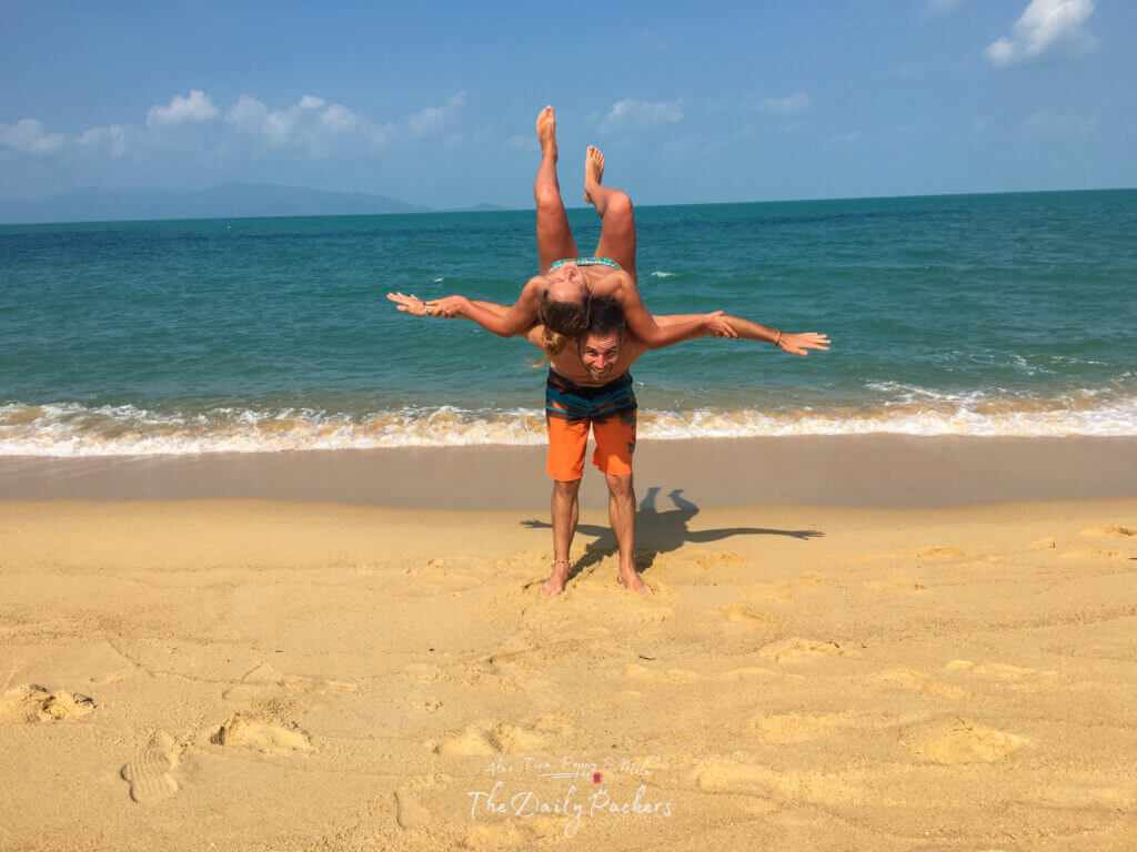 Couple playing on the golden sandy beach with turquoise sea and clear blue sky in the background in Koh Samui