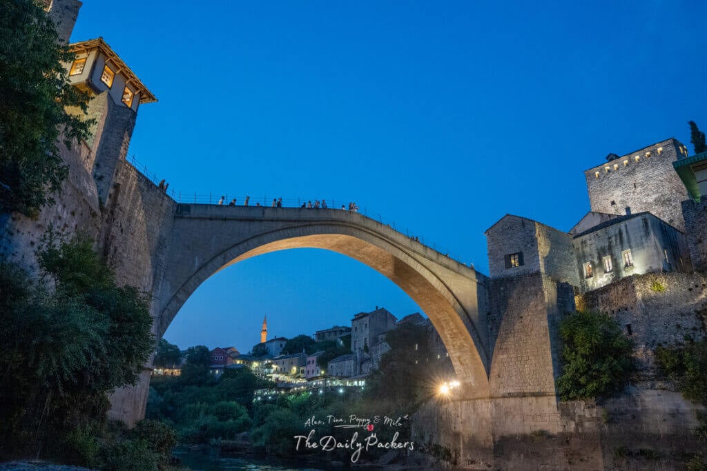 Le pont de Stari Most vu d'en bas la nuit, éclairé de façon spectaculaire par le minaret et les bâtiments de la vieille ville à l'arrière-plan.