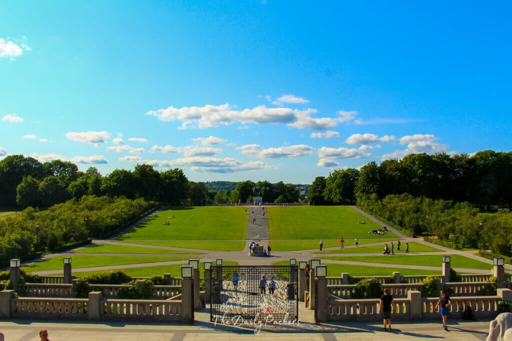 Grande pelouse verte et allées dans le parc Vigeland, Oslo, avec des gens qui se promènent et se détendent.