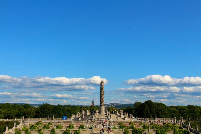 Monolith sculpture in Vigeland Park with crowds and dramatic sky in the background