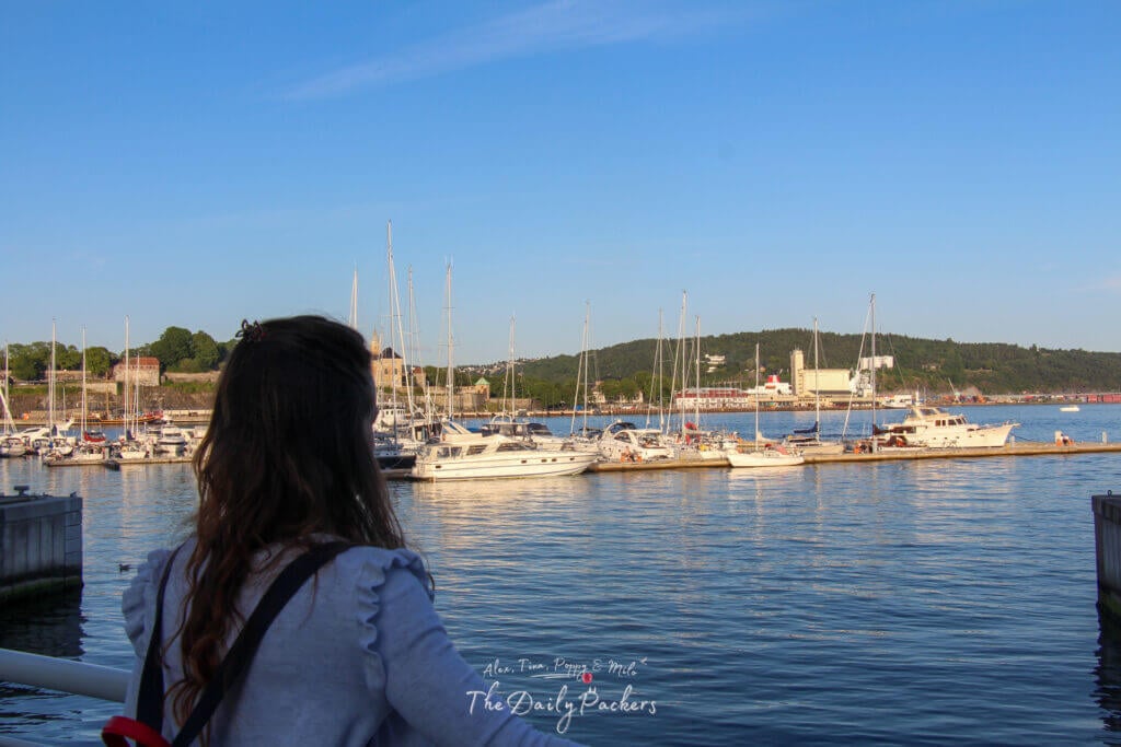 Femme regardant les bateaux amarrés dans la marina d'Oslo au coucher du soleil
