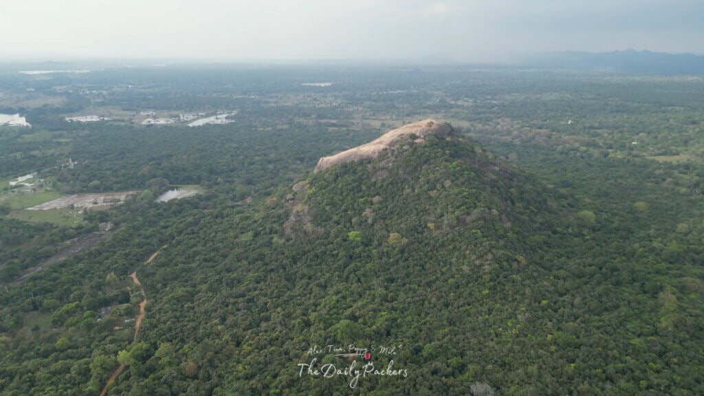 Vue d'ensemble du paysage depuis le sommet du Pidurangala, avec vue sur les plaines boisées et les collines lointaines.