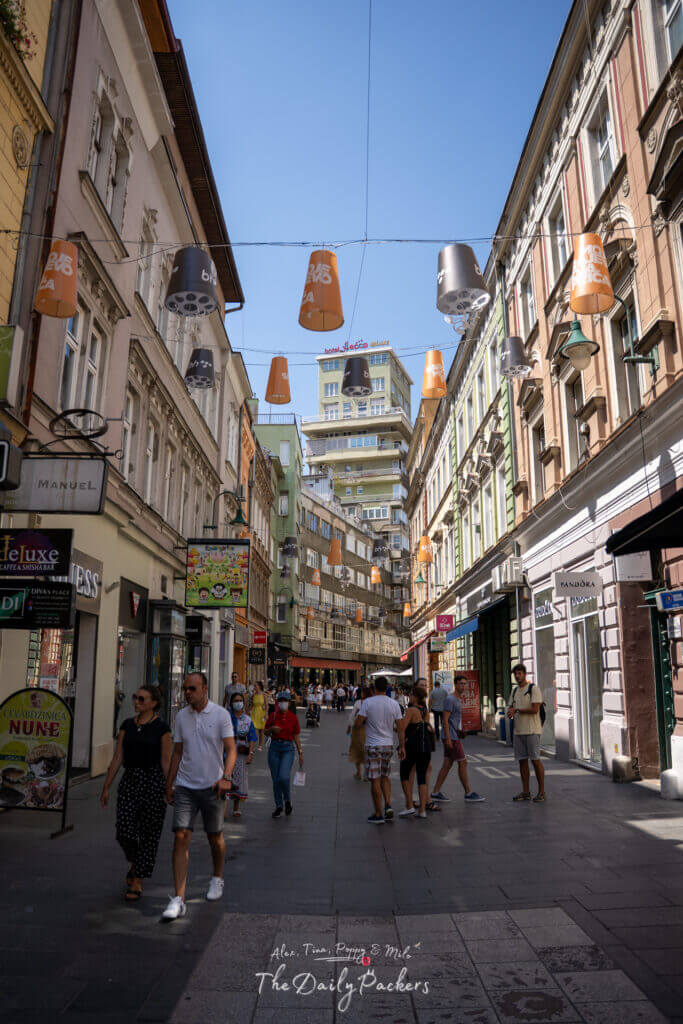 La rue Ferhadija est remplie de gens qui se promènent sous les décorations suspendues.