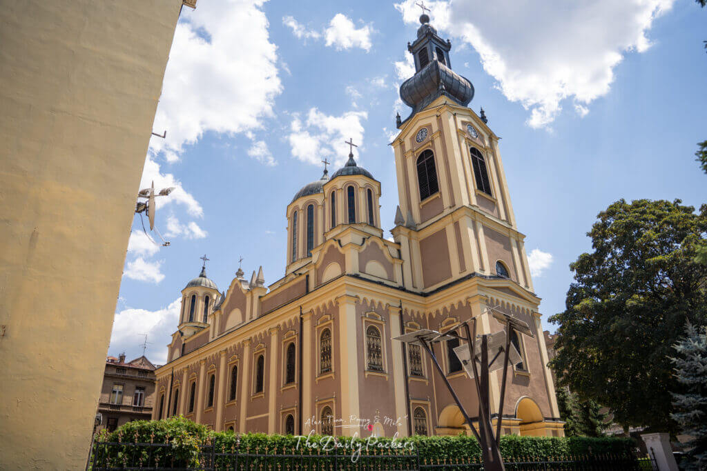 Vue latérale de la cathédrale de la Nativité de la Théotokos à Sarajevo, montrant les dômes et la façade jaune ornée.