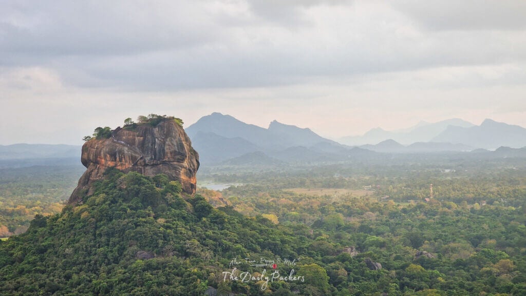 Coucher de soleil sur le rocher du lion de Sigiriya, entouré de brume et de nuages spectaculaires au-dessus de la forêt dense.