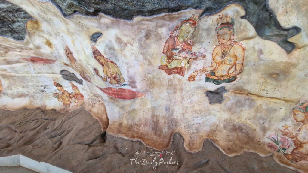 Fresques anciennes de femmes sur une paroi rocheuse à l'intérieur du complexe de Sigiriya, montrant des expressions et des ornements détaillés.