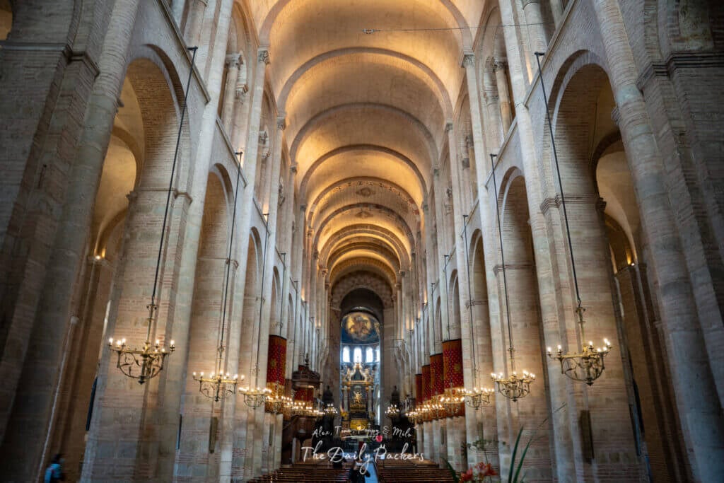 Interior of the Basilica of Saint-Sernin with tall Romanesque arches and warm lighting.