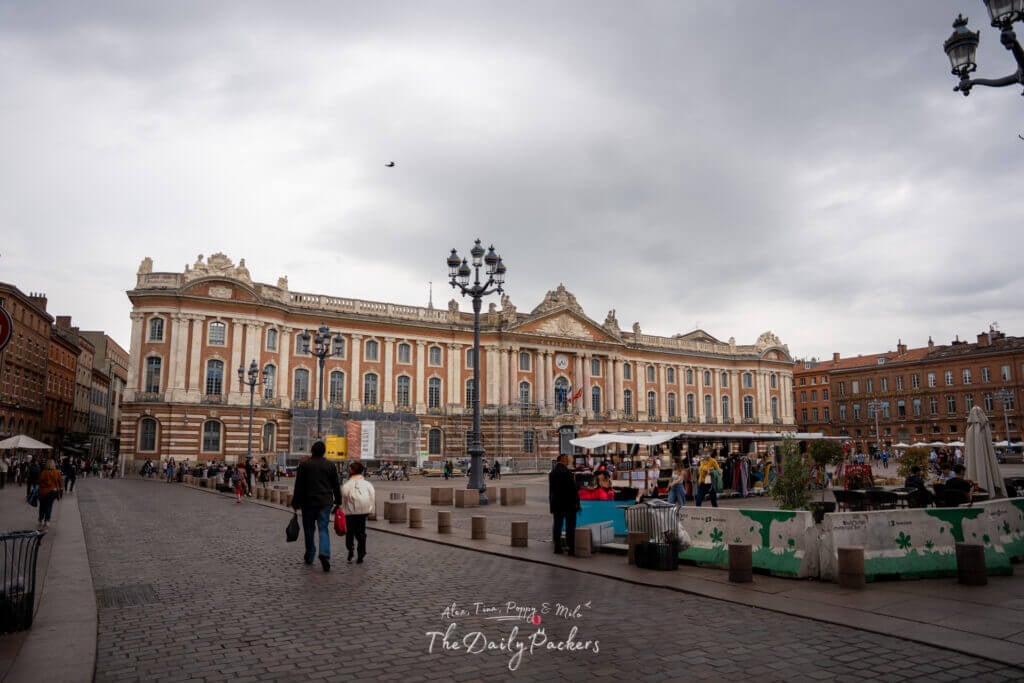 Wide view of Place du Capitole with its grand neoclassical city hall and bustling square.