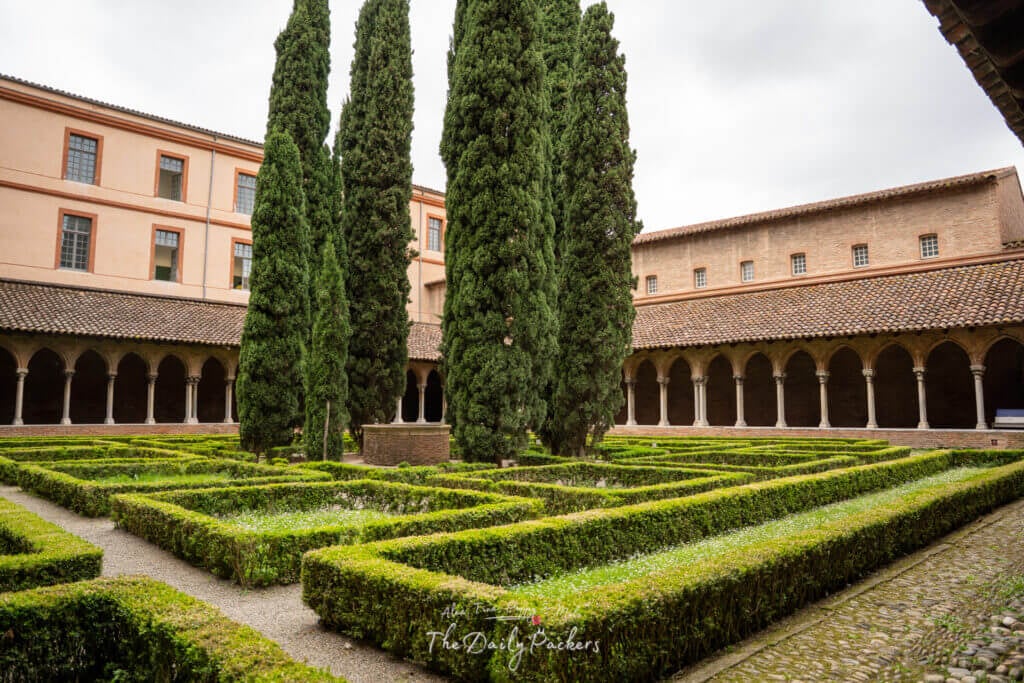 Central courtyard of the Jacobins Convent featuring a symmetrical garden and Romanesque arcades.