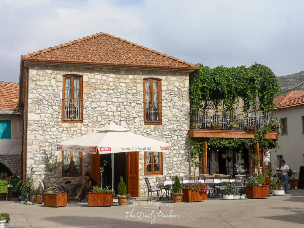 Charming restaurant terrace with stone facade, green vines, and a welcoming courtyard in Trebinje.