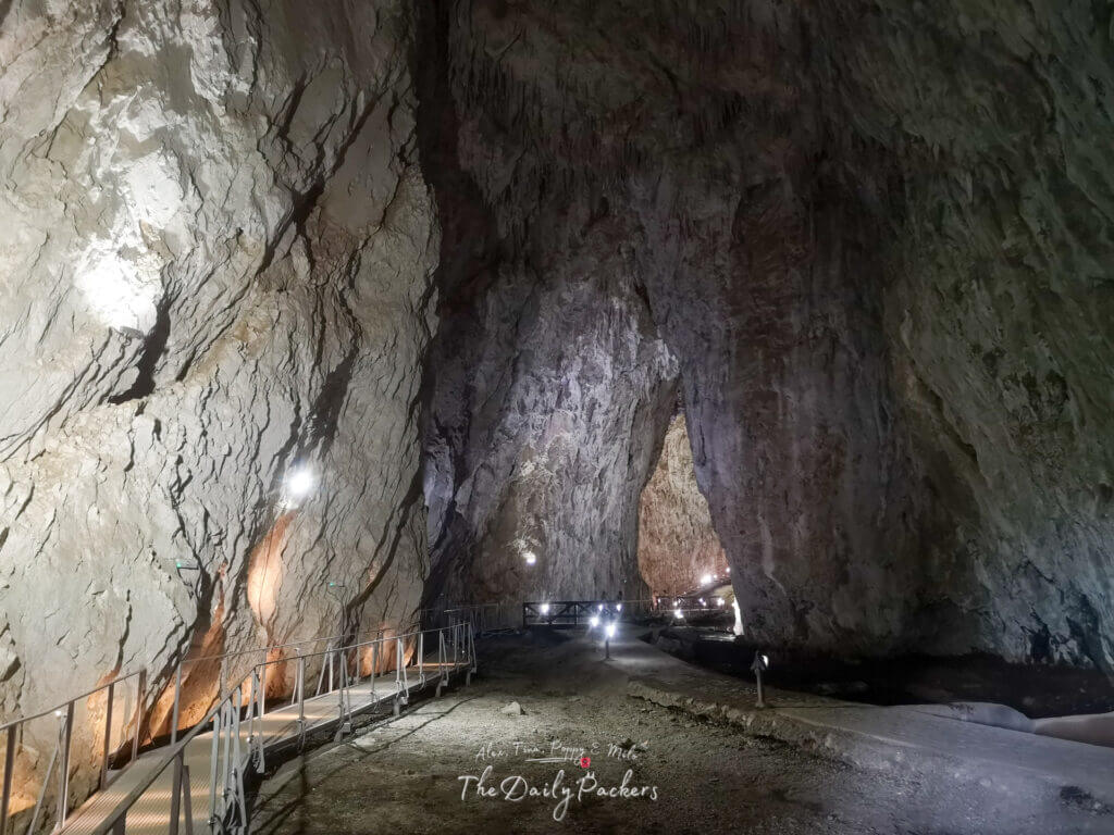 Illuminated pathway inside Stopića Cave with towering rock walls and natural textures.