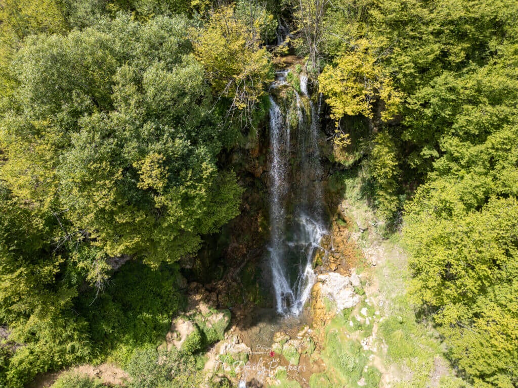 Drone view of Gostilje Waterfalls cascading through lush green forest in Zlatibor