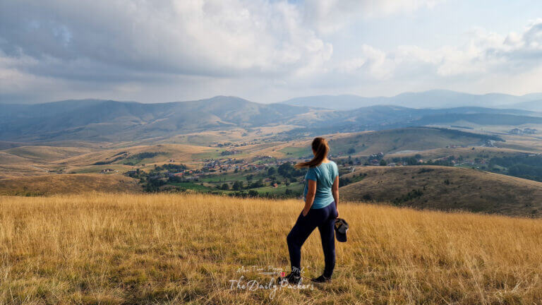 Pregnant woman standing on a golden hilltop overlooking a wide valley and distant mountains in Zlatibor, Serbia