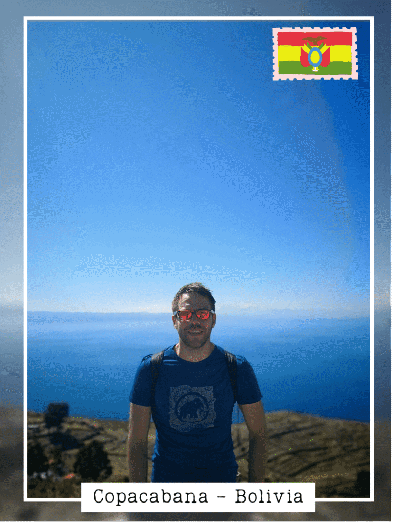 homme en chemise bleue avec sac à dos devant le lac Titicaca bleu foncé à Copacabana en Bolivie