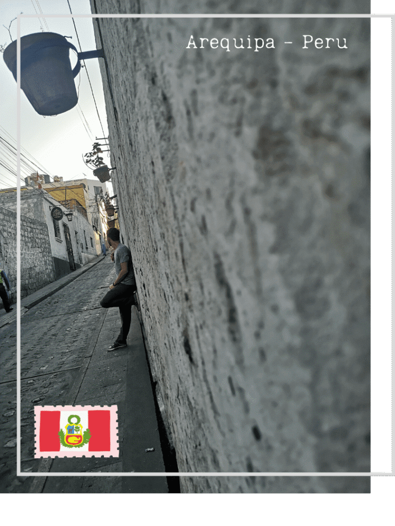 homme adossé à un mur de pierre volcanique blanche dans une rue étroite d'Arequipa au Pérou