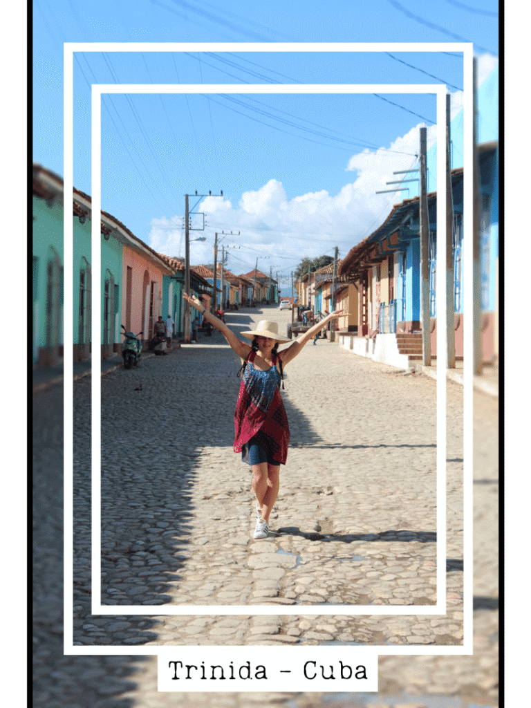 Femme debout dans une rue pavée bordée de maisons coloniales colorées à Trinidad Cuba