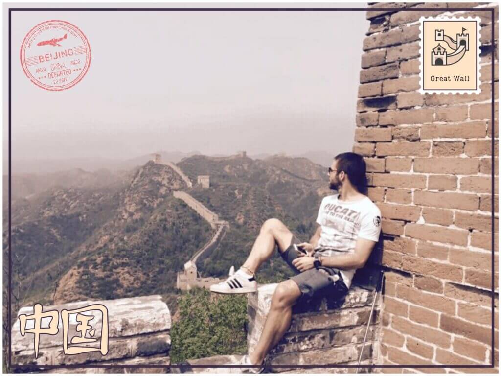 Homme assis sur la Grande Muraille de Chine regardant les montagnes par une journée brumeuse