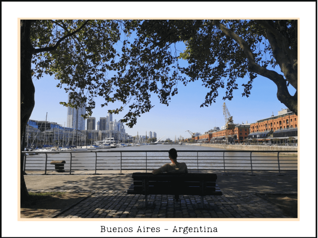 Homme assis sur un banc sous les arbres, regardant le front de mer et la ligne d'horizon à Buenos Aires, Argentine.