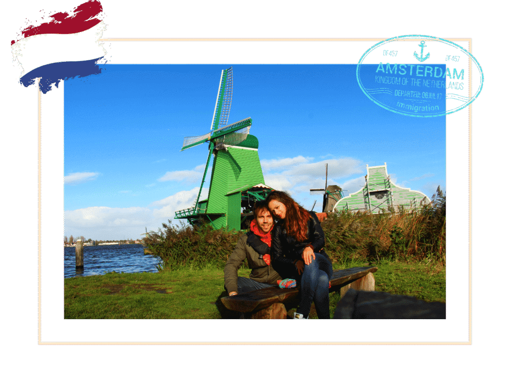 Couple assis sur un banc devant des moulins à vent verts traditionnels le long d'un canal aux Pays-Bas.