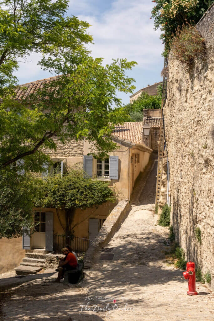 Steep cobblestone path winding between stone houses with pastel shutters in Gordes old town