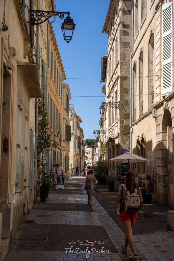 Rue calme du quartier de la Roquette à Arles, bordée de bâtiments historiques en pierre et de volets pastel.