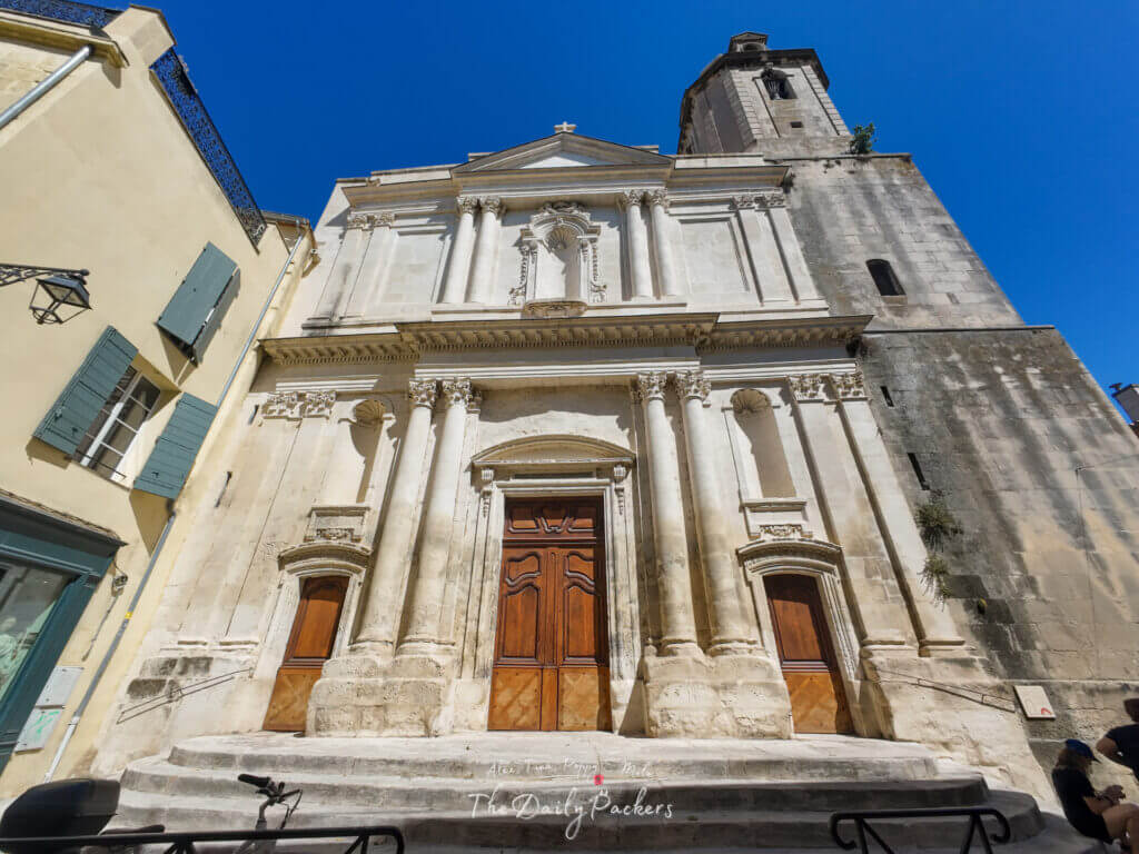 Façade de l'église Saint-Trophime à Arles avec de hautes colonnes et des portes en bois sous un ciel bleu profond