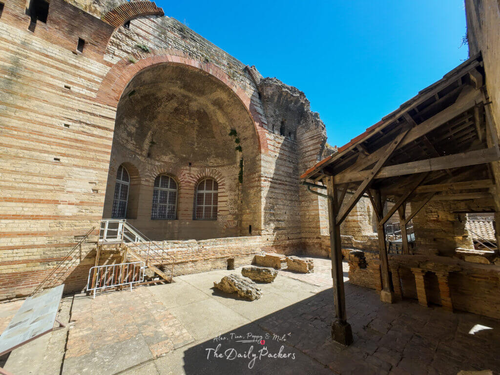 Intérieur des ruines des anciennes thermes romaines d'Arles, avec des murs de briques et des arches partiellement dans l'ombre.