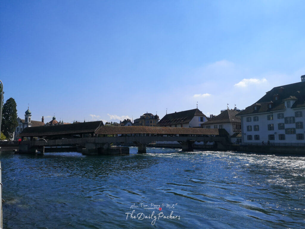Covered wooden Spreuer Bridge spanning the Reuss River in Lucerne, with old town buildings in the background.