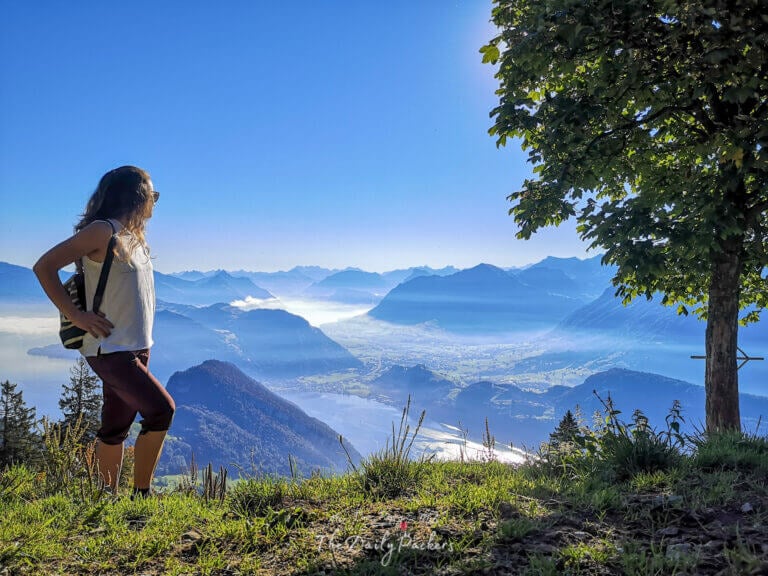 Woman standing on a mountain ridge admiring the panoramic view over Lake Lucerne and the surrounding Alps from Mount Pilatus.