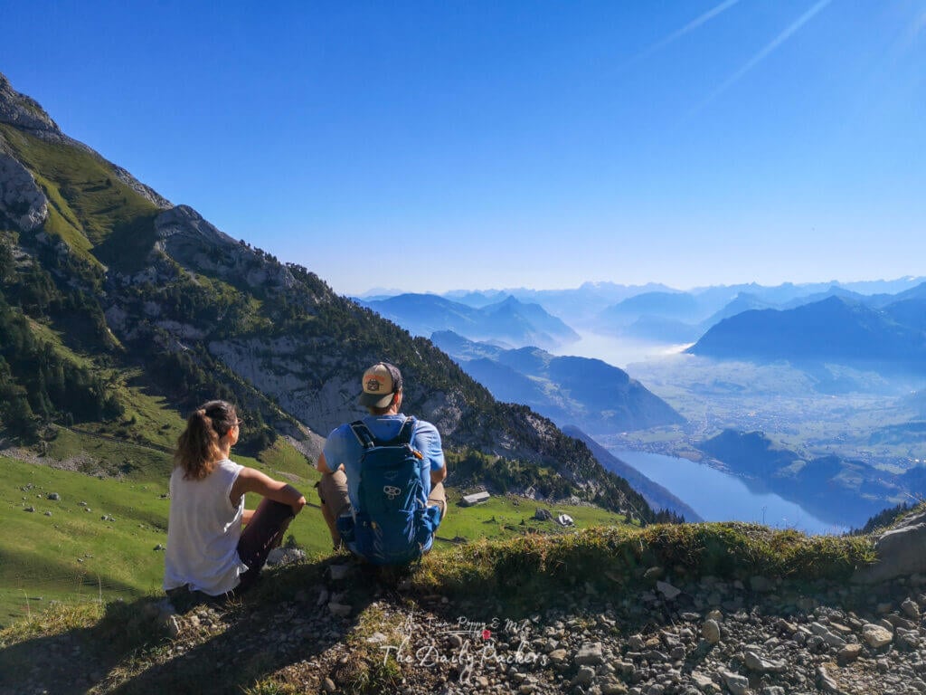 Couple assis sur une pente herbeuse surplombant la vallée et les lacs du Mont Pilatus près de Matthorn.