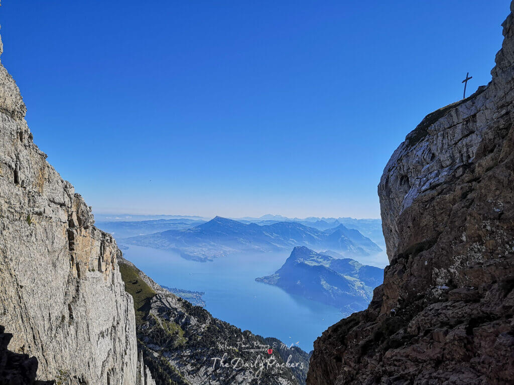 Sentier de montagne serpentant à travers un terrain rocailleux et offrant des vues panoramiques sur des sommets lointains sous un ciel bleu éclatant.