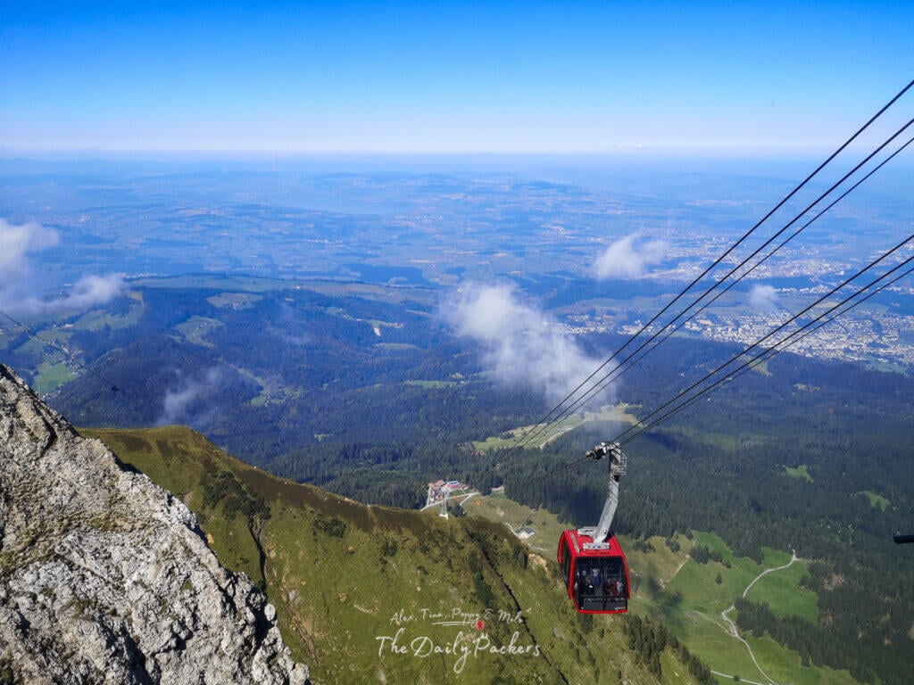 Le téléphérique rouge monte au Mont Pilatus et offre une vue imprenable sur la campagne suisse verdoyante et les villes lointaines en contrebas.
