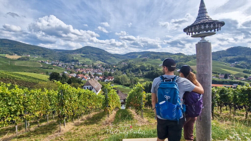Surplombant les vignobles de Sasbachwalden, un couple s'embrasse tout en admirant la vue panoramique sur les collines de la Forêt-Noire et la ville en contrebas.