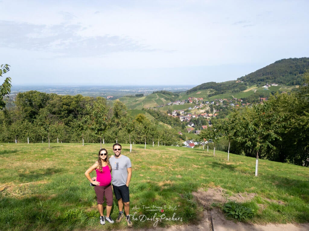 Point de vue sur les vignobles de Sasbachwalden avec un couple debout sur une colline herbeuse, entourée de collines ondulantes.
