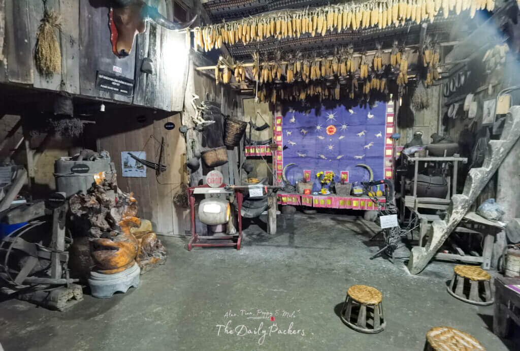 Traditional workshop in Cat Cat Village with hanging corn, woven baskets, wooden tools, and cultural decorations.