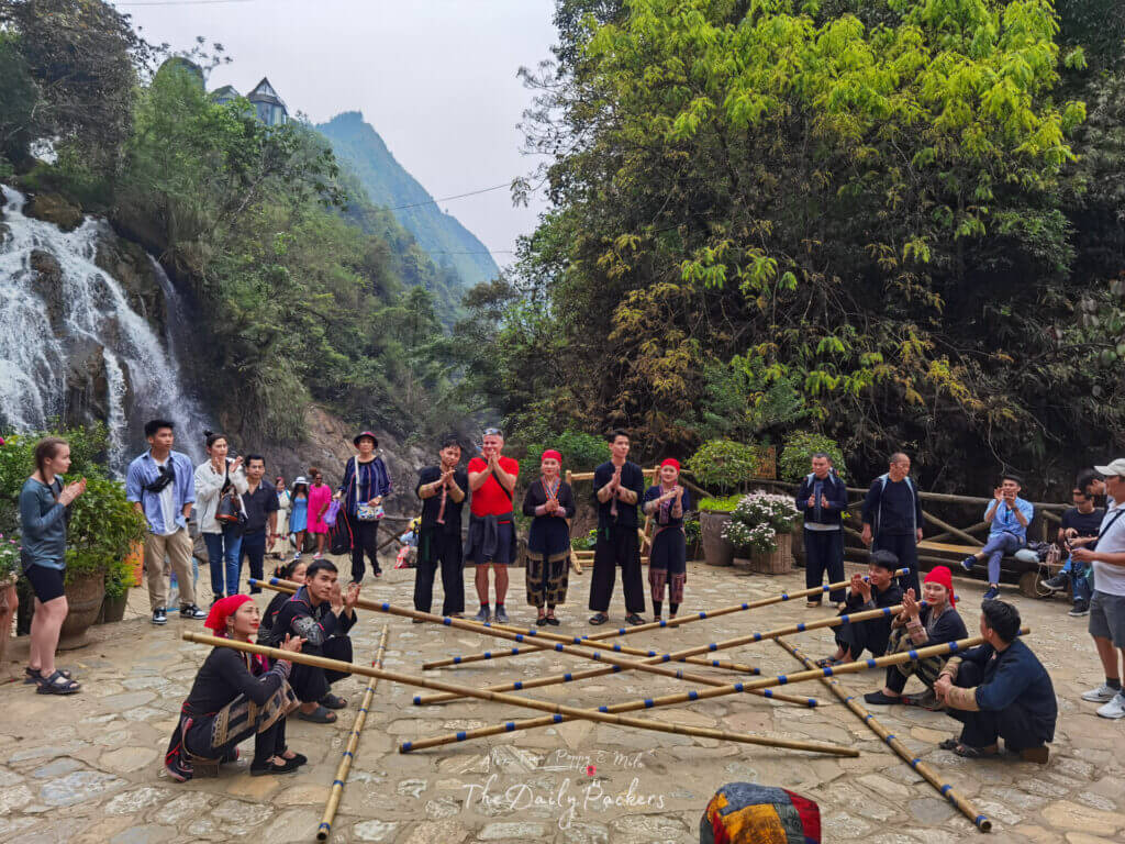 Traditional dance performance in Cat Cat Village with locals in ethnic costumes and bamboo poles.
